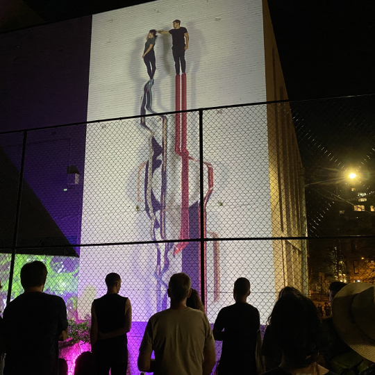 Projection on wall at night of people dancing 